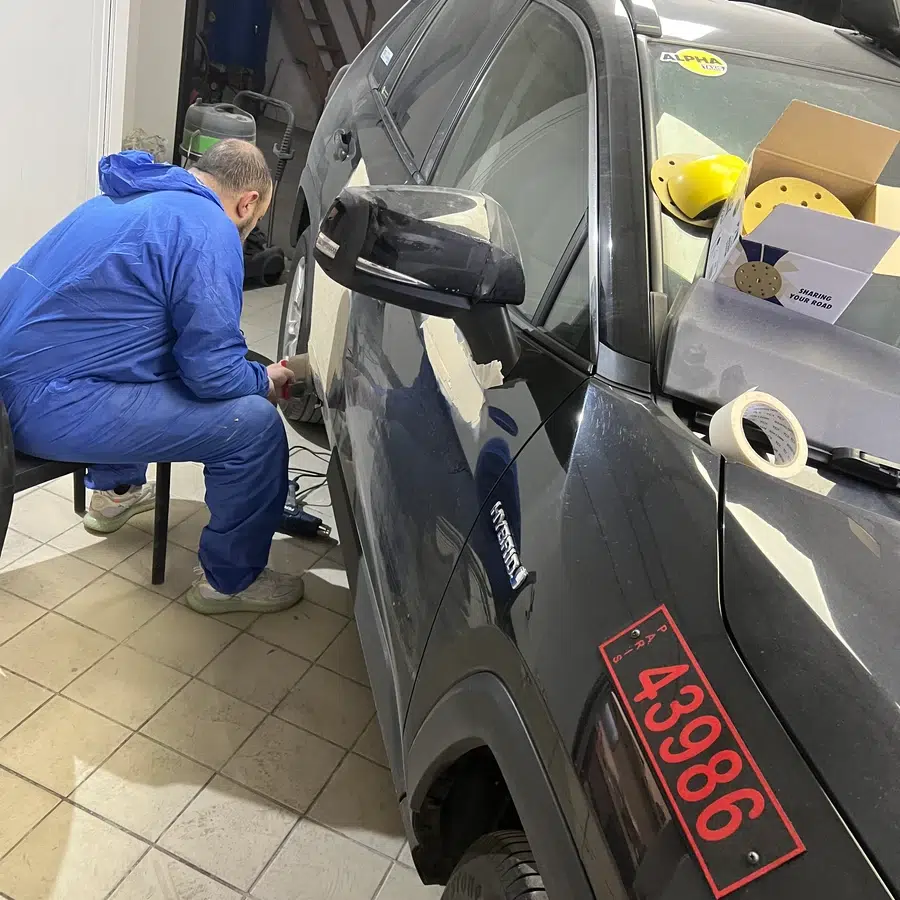 Réparation automobile en cours Homme réparant une voiture dans un atelier